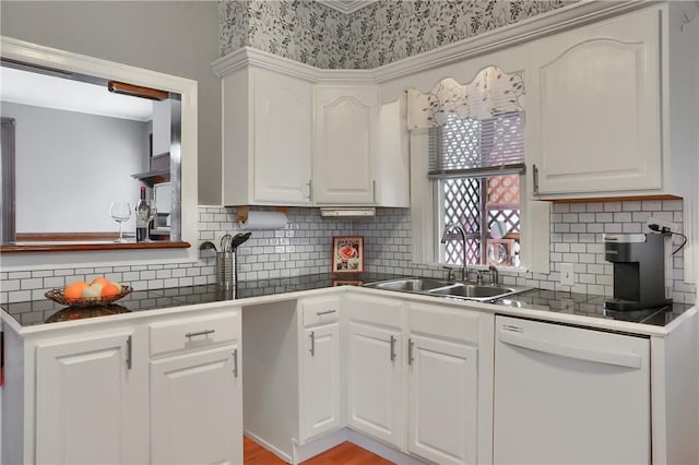 kitchen with dark countertops, white dishwasher, and white cabinets