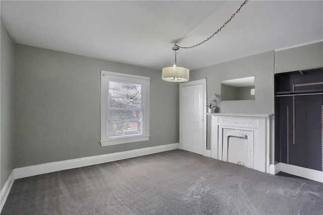 unfurnished living room featuring baseboards and dark colored carpet