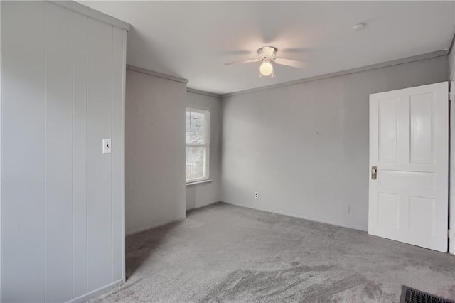 unfurnished room with light carpet, ceiling fan, visible vents, and ornamental molding