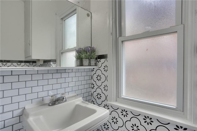 bathroom with a sink, tile walls, decorative backsplash, and a wealth of natural light