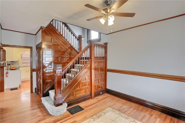 staircase featuring ornamental molding, visible vents, baseboards, and wood finished floors