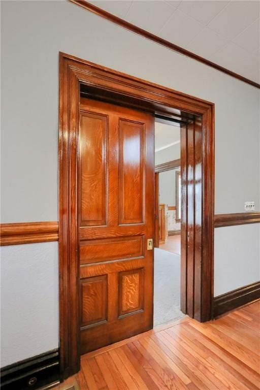 corridor featuring ornamental molding and light wood finished floors