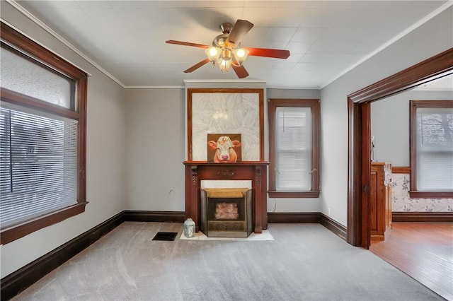 living area featuring crown molding, a fireplace with flush hearth, visible vents, and a healthy amount of sunlight