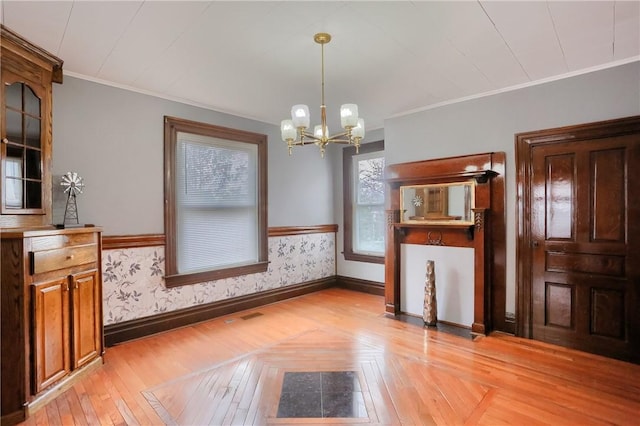 unfurnished dining area featuring ornamental molding, a wainscoted wall, and wallpapered walls