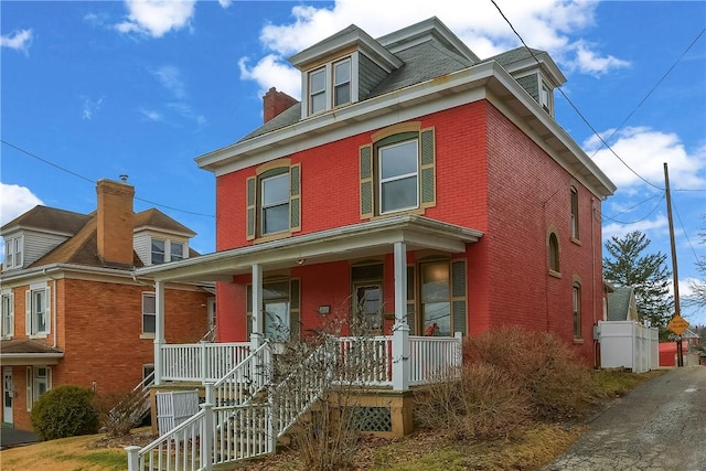 american foursquare style home with covered porch and brick siding