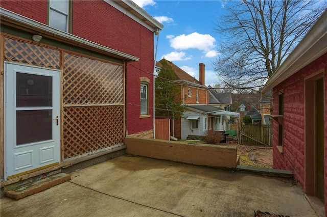 view of home's exterior with brick siding, a patio area, fence, and a residential view