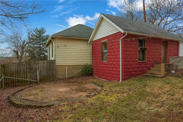 view of side of home featuring a yard, fence, and roof with shingles