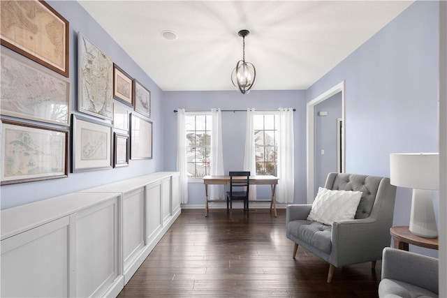 sitting room featuring an inviting chandelier, baseboards, and dark wood finished floors