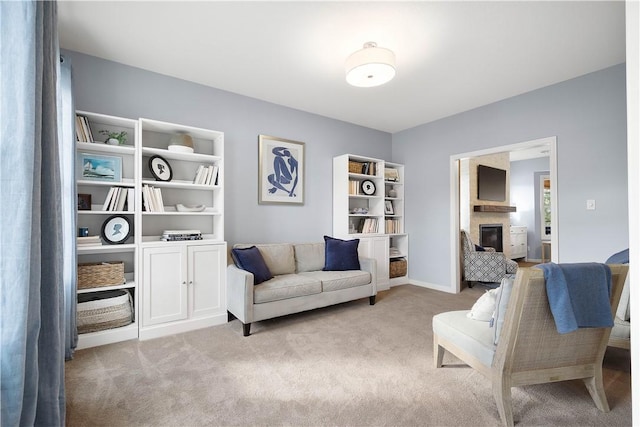 living area featuring a glass covered fireplace and light colored carpet