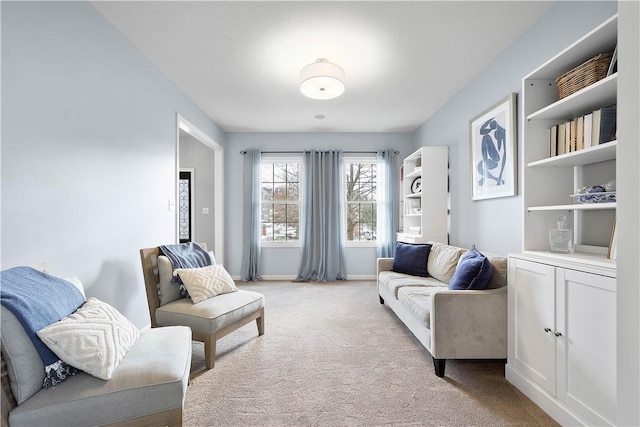 sitting room featuring light colored carpet and baseboards