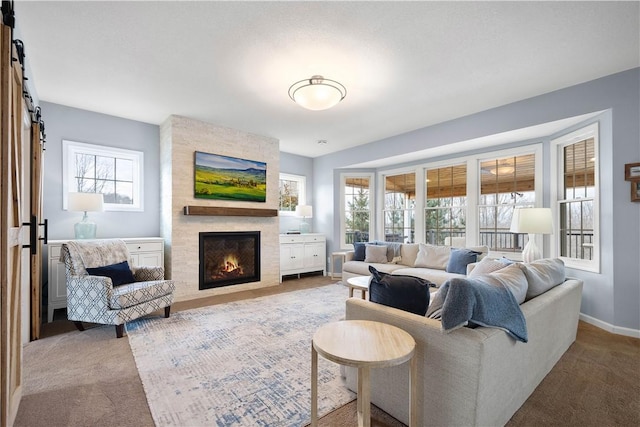 living room with light carpet, a barn door, a fireplace, and baseboards