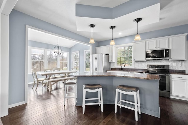 kitchen with a breakfast bar, appliances with stainless steel finishes, white cabinets, and a center island