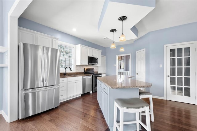 kitchen featuring appliances with stainless steel finishes, a center island, white cabinets, and light stone countertops