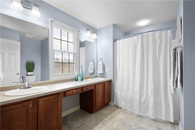 bathroom with visible vents, a sink, and double vanity