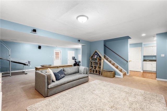 living room with light carpet, a textured ceiling, baseboards, and stairs