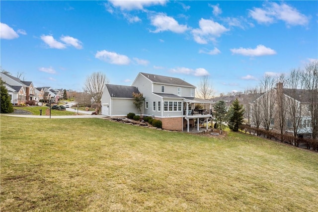 back of property with a garage, a residential view, a sunroom, and a yard