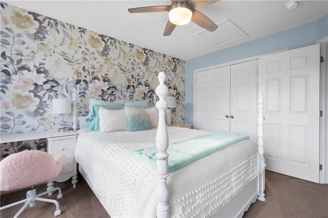 bedroom with wallpapered walls, attic access, dark colored carpet, and a closet