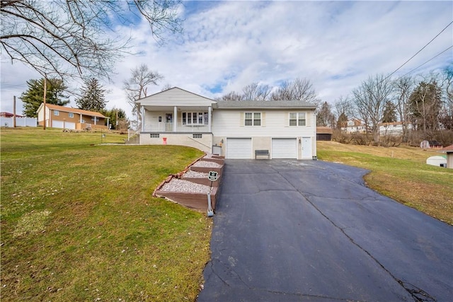 raised ranch featuring a garage, a front lawn, a porch, and aphalt driveway