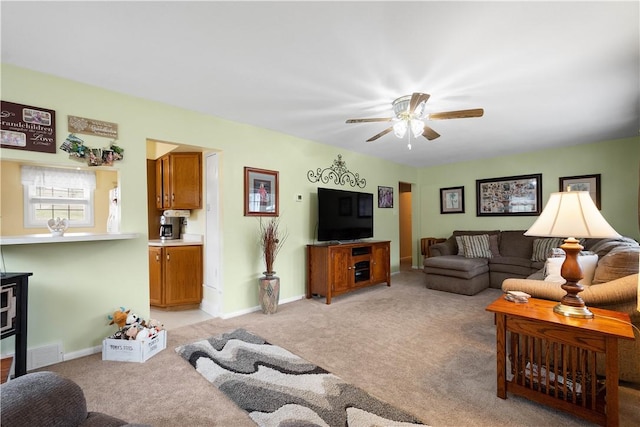 living room featuring a ceiling fan, light colored carpet, visible vents, and baseboards