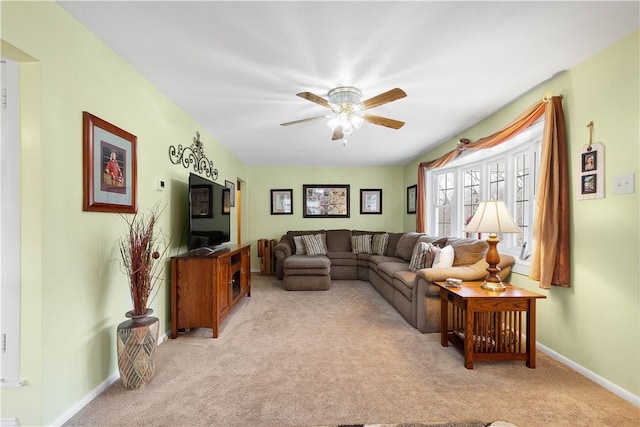 living area featuring ceiling fan, baseboards, and light colored carpet