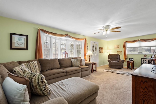 carpeted living area with ceiling fan, baseboards, and a healthy amount of sunlight