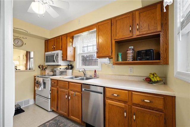 kitchen with white electric stove, visible vents, light countertops, stainless steel dishwasher, and brown cabinetry