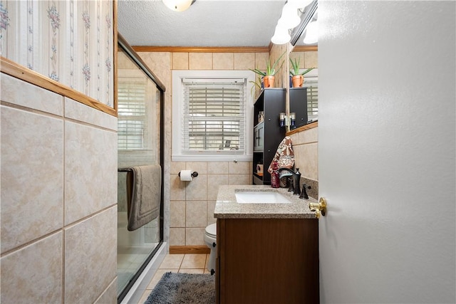 full bathroom featuring toilet, tile patterned floors, vanity, a shower stall, and tile walls