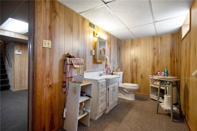 bathroom with toilet, wooden walls, visible vents, and vanity