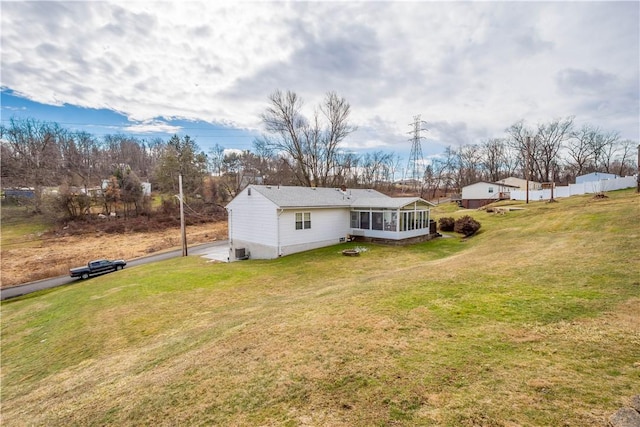 back of property featuring a sunroom, central AC unit, and a yard