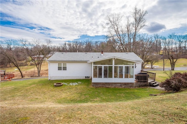 back of house with a sunroom, a lawn, a fire pit, and a wooden deck