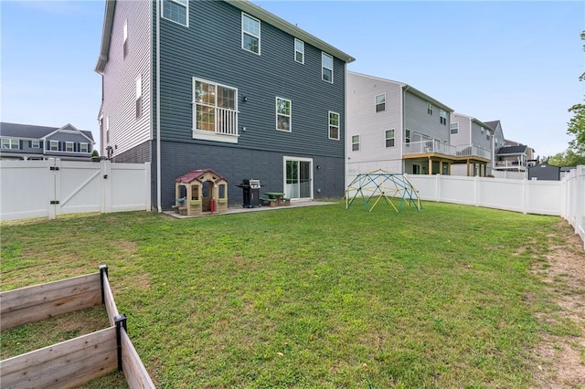 rear view of house with a garden, a gate, a fenced backyard, and a lawn