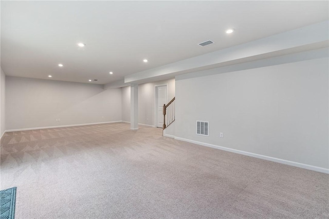 finished below grade area with light colored carpet, visible vents, recessed lighting, and stairs