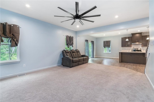 living room with plenty of natural light, dark carpet, visible vents, and baseboards