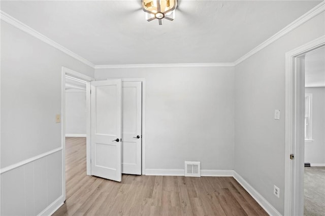 spare room featuring visible vents, crown molding, light wood-style flooring, and baseboards