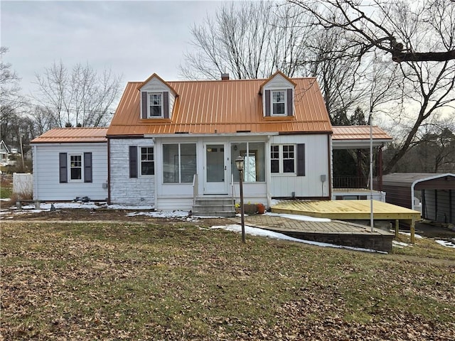 cape cod home with entry steps, metal roof, and a front yard