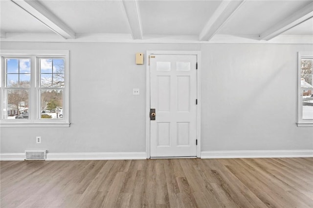 entrance foyer with beam ceiling, light wood-style flooring, visible vents, and baseboards