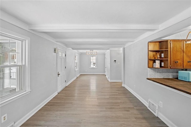 interior space with an inviting chandelier, light wood-style flooring, baseboards, and beamed ceiling