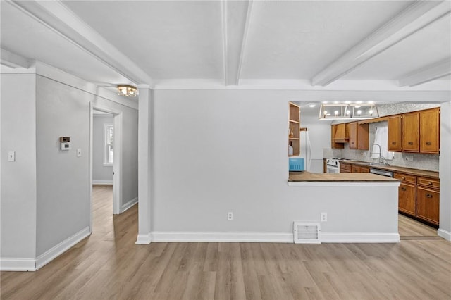 kitchen featuring brown cabinets, visible vents, backsplash, a sink, and beamed ceiling