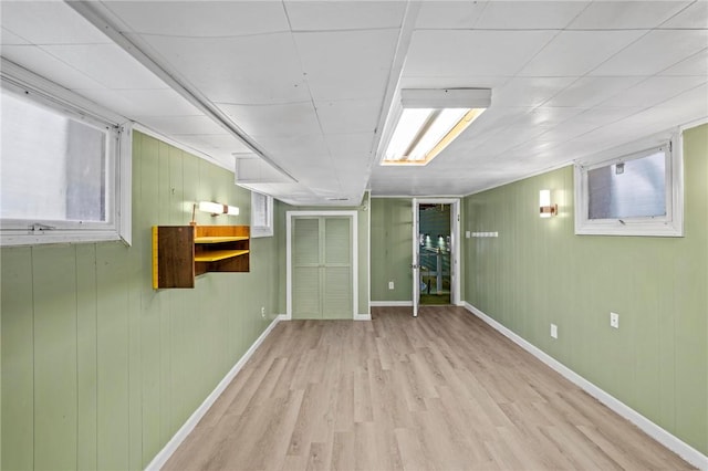 basement featuring light wood-style floors, a healthy amount of sunlight, and baseboards