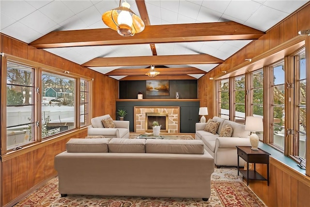 living area featuring a healthy amount of sunlight, wood walls, and lofted ceiling with beams