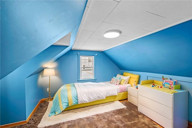 bedroom featuring lofted ceiling, dark carpet, and baseboards