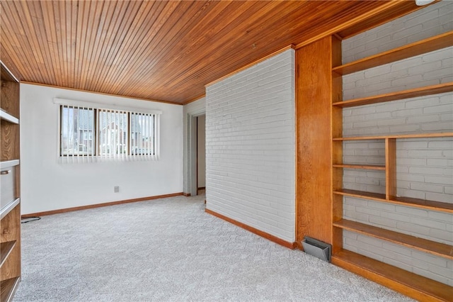 spare room with crown molding, wood ceiling, light carpet, brick wall, and baseboards