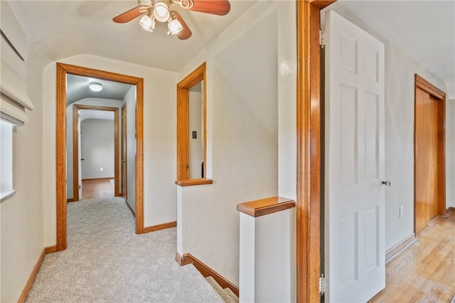 hallway featuring light colored carpet and baseboards