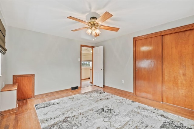 unfurnished bedroom with ceiling fan, light wood-style flooring, visible vents, baseboards, and a closet