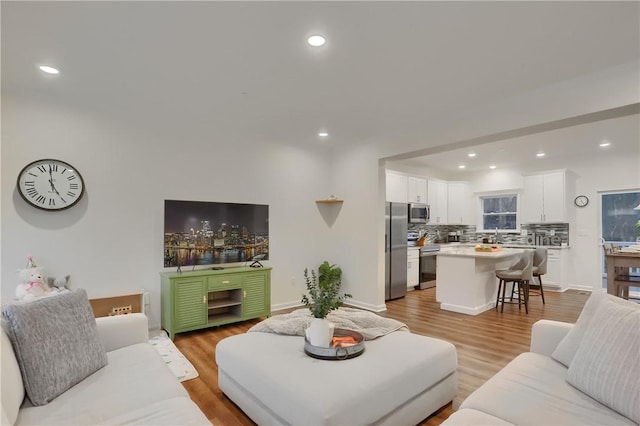 living area with light wood-style flooring and recessed lighting