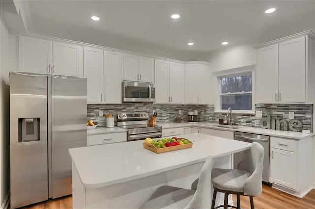 kitchen featuring white cabinetry, stainless steel appliances, a sink, and light countertops