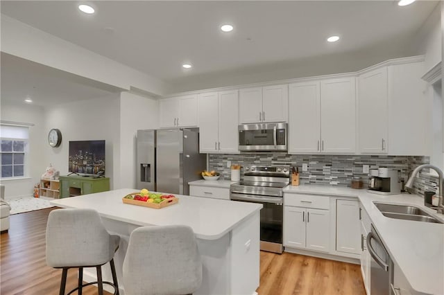 kitchen featuring white cabinetry, stainless steel appliances, a sink, and light countertops