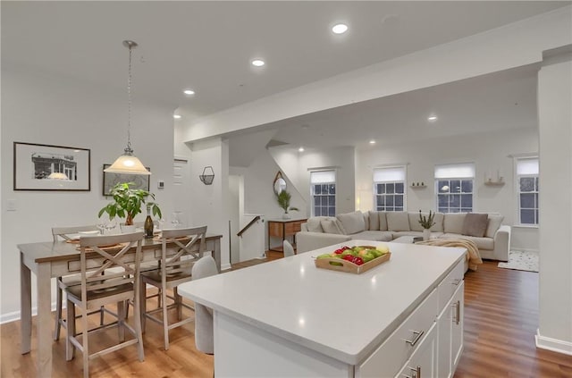 kitchen with light countertops, pendant lighting, white cabinets, and a kitchen island