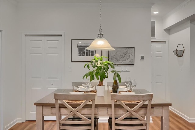 dining room featuring crown molding, baseboards, and wood finished floors