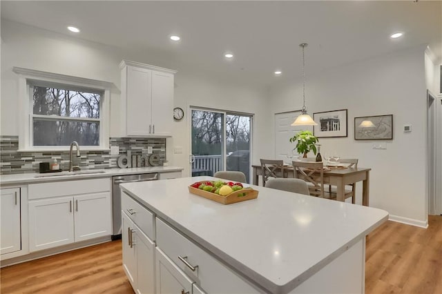 kitchen featuring dishwasher, light countertops, a kitchen island, and white cabinetry